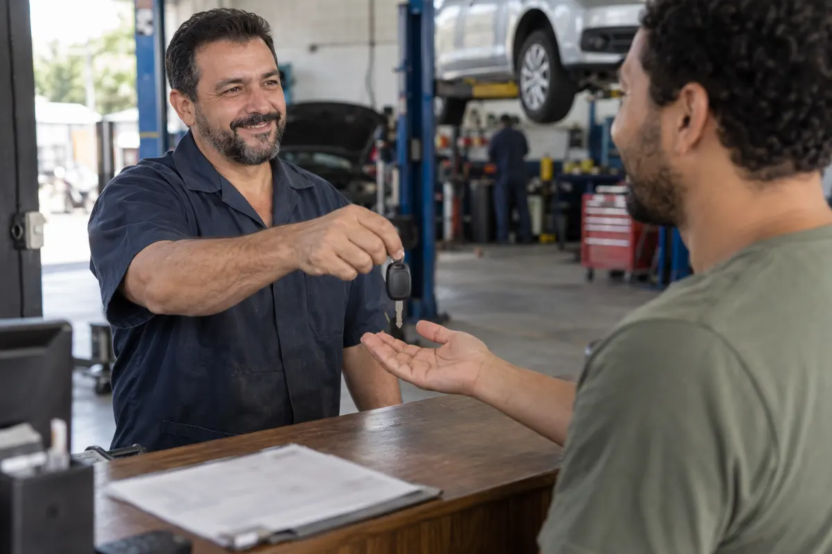 Dono da oficina entregando a chave do carro a um cliente satisfeito no balcão